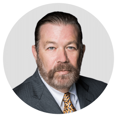 Man with a beard in a suit and patterned tie.