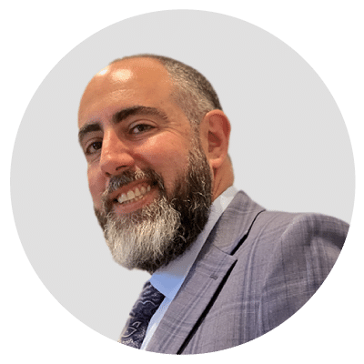 Man with a beard wearing a suit and tie, smiling.