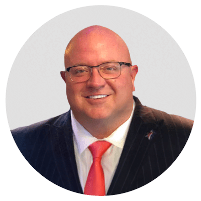 Man in a suit with glasses and a red tie, smiling in a circular frame. Man in a suit with glasses and a red tie, smiling in a circular frame.