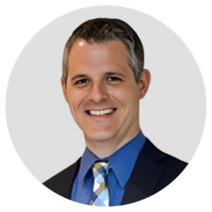 A smiling person in a suit and tie, set against a plain background.