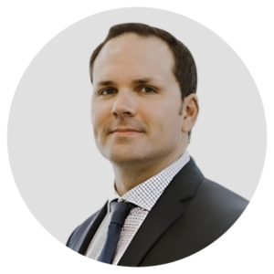 Man in a suit and tie with a neutral expression against a light background.