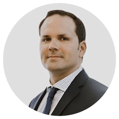 Man in a suit and tie with a neutral expression against a light background.