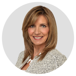 A woman with shoulder-length hair wearing a light-colored jacket, smiling at the camera.
